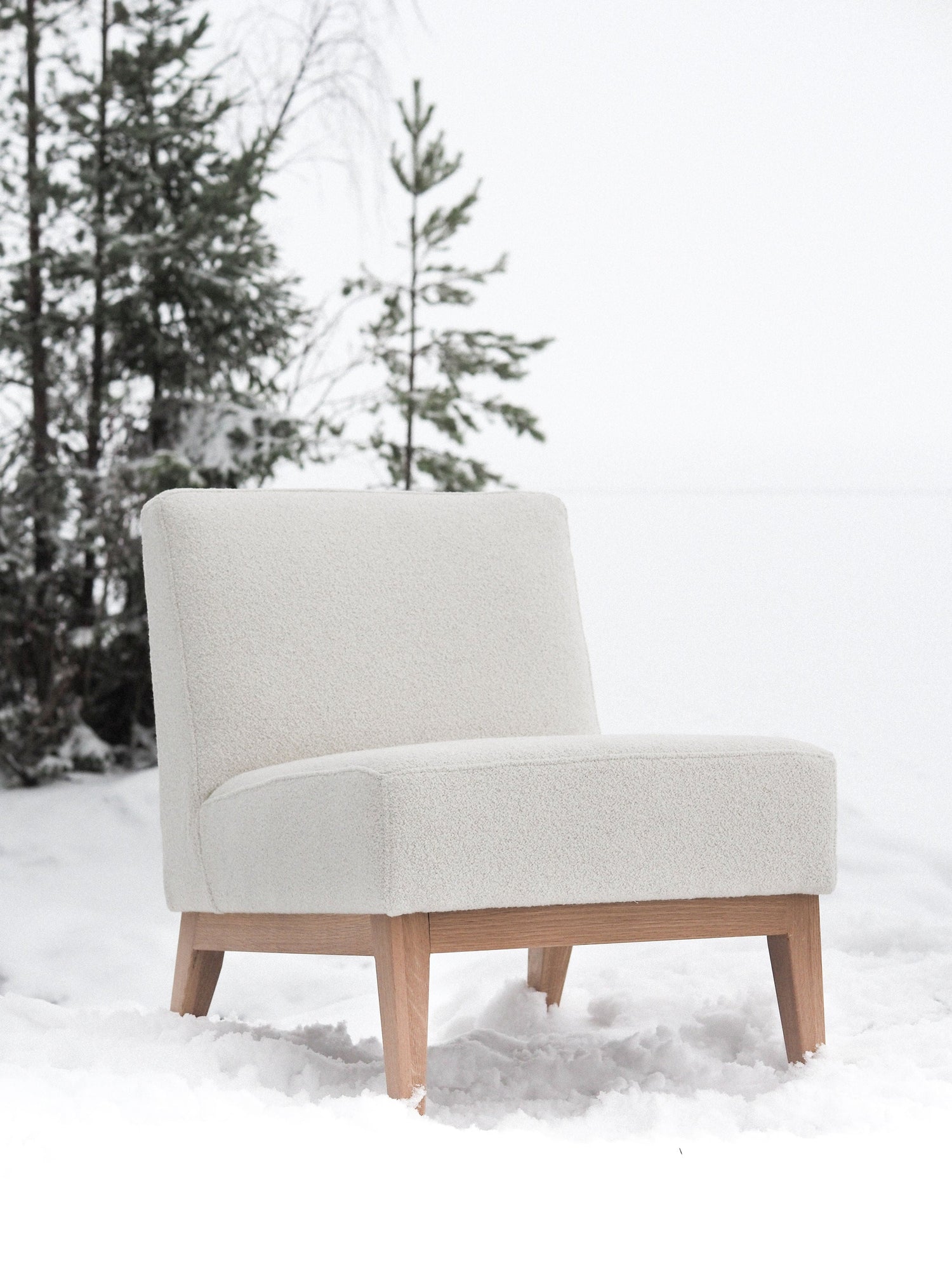 Nagu-nojatuoli valkoisella kankaalla verhoiltuna. Jalat ja kehikko tammea.